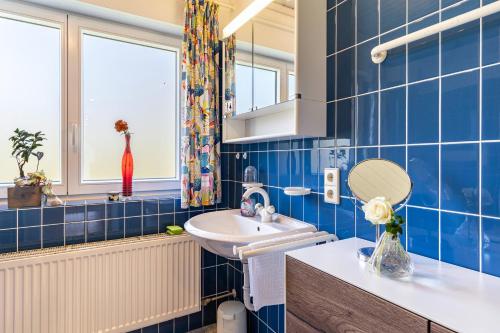 Baño de azulejos azules con lavabo y espejo en Ferienwohnung Anne und Peter Bosch, en Alpirsbach