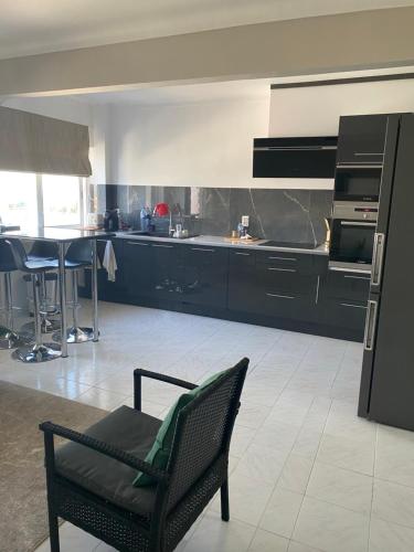 una cocina con armarios negros, una silla y una mesa en Casa Alves, en Palmela