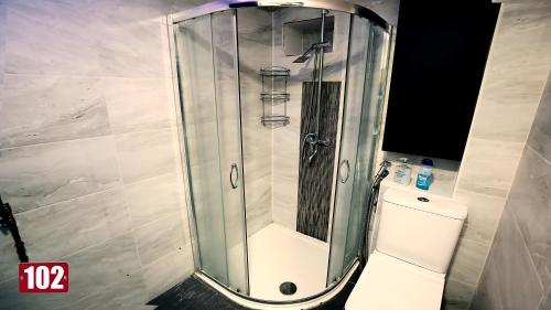 une douche avec une porte en verre à côté des toilettes dans l'établissement Shut Eyes, à Londres