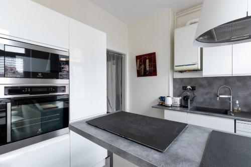 une cuisine avec des armoires blanches et un comptoir noir dans l'établissement Le Grand Patural, à Ban-Saint-Martin