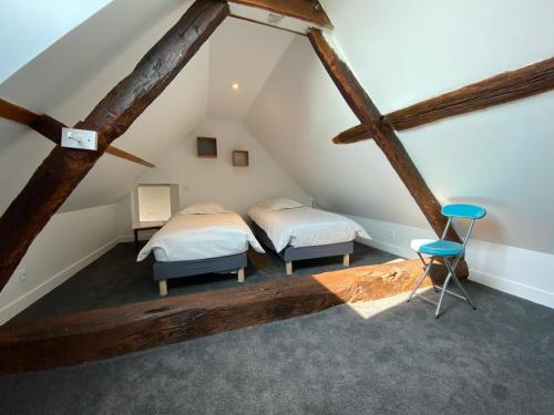 two beds in a attic room with wooden beams at Gîte du Petit Rocher SAINTE SUZANNE in Sainte-Suzanne