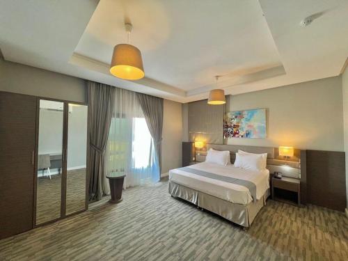 a bedroom with a large bed and a large window at Loren Suites Corniche in Jeddah