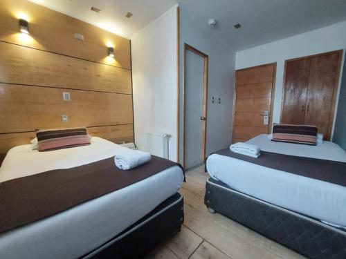 Duas camas num quarto com paredes de madeira em Hotel Angelmontt em Puerto Montt