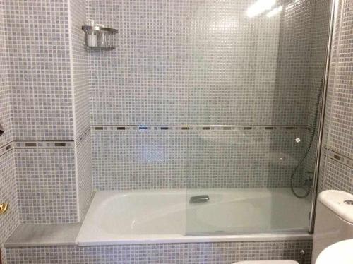 y baño con bañera y ducha de azulejos. en Asturias Boho Chic en Aller
