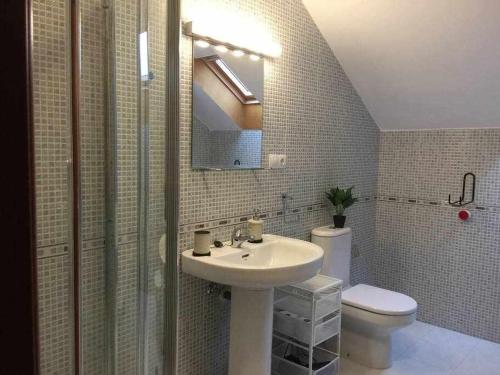 ein Badezimmer mit einem Waschbecken, einem WC und einem Spiegel in der Unterkunft Encanto Asturiano 