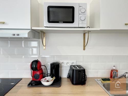 a kitchen with a microwave on a counter with aether at Les studios d'Elina - Entrée autonome in Châtellerault