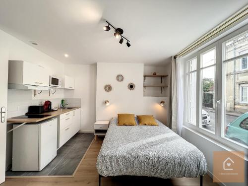 a bedroom with a bed and a kitchen with a window at Les studios d'Elina in Châtellerault