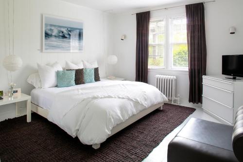 1 dormitorio blanco con 1 cama y TV en Sole East Resort, en Montauk