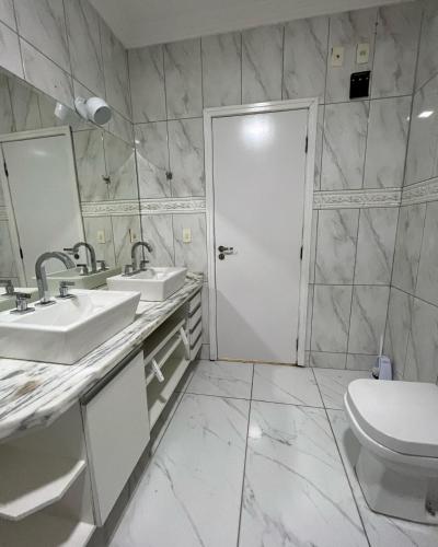 a bathroom with two sinks and a toilet at CasaparkIndaiatuba in Indaiatuba
