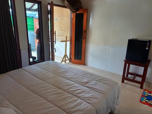 a bedroom with a bed and a television in it at Black Sweet Bungalow in Gili Air