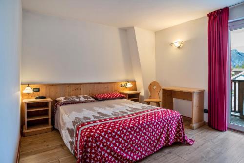 a bedroom with a bed with a red and white blanket at Giongo Residence Aparthotel 101 in Lavarone