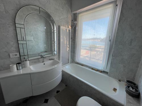 uma casa de banho com um lavatório, uma banheira e uma janela em Sogno sul mare em Sestri Levante