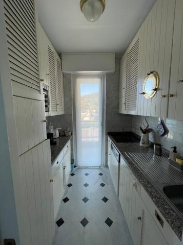 uma cozinha com armários brancos e piso em azulejo em Sogno sul mare em Sestri Levante