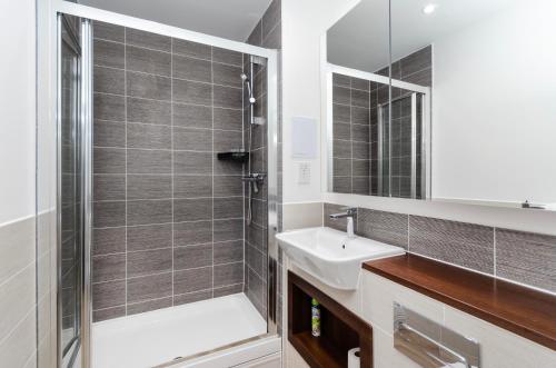 W łazience znajduje się prysznic, umywalka i lustro. w obiekcie Stylish 2 BR Flat in Wandsworth w Londynie