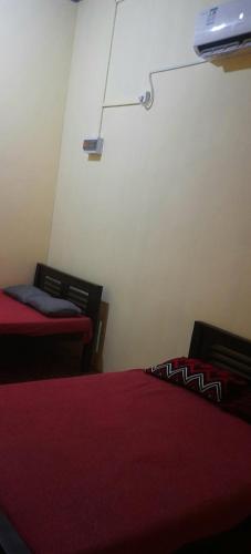 um quarto com 2 camas com lençóis vermelhos e um candeeiro em My guest rooms kattankudy em Kattankudi