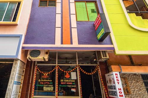 uma frente de loja com um edifício roxo e amarelo em SPOT ON Venkata Sai Residency em Tirupati