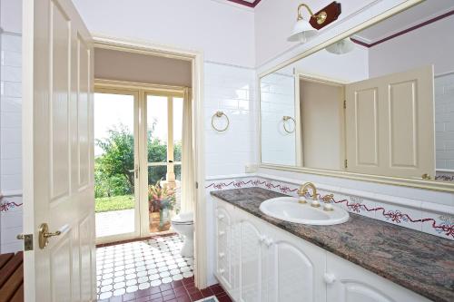 a bathroom with a sink and a mirror and a toilet at Tranquil Garden Hideaway in Ormeau