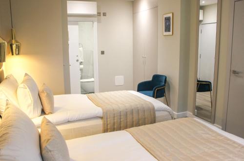 a hotel room with two beds and a blue chair at NOX Richmond in Richmond