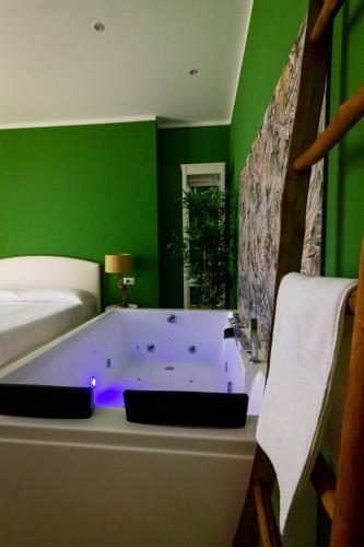 a green room with a tub in a bedroom at COMÓ EXCLUSIVE in Aprilia