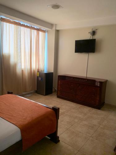 1 dormitorio con cama, TV y tocador en Hotel Deseos en Guayaquil