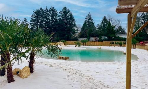 a swimming pool in a backyard with sand and palm trees at Glamping Payrac in Payrac