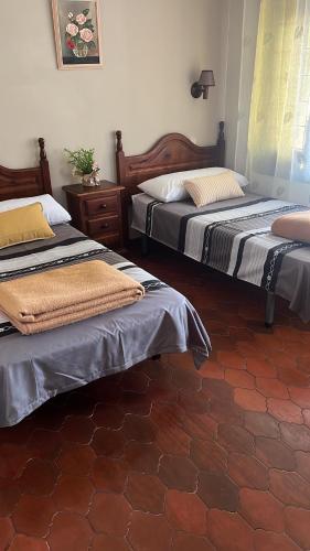 2 łóżka w pokoju z podłogą wyłożoną kafelkami w obiekcie Hostal Sabor Fusion w mieście La Pradera de Navalhorno