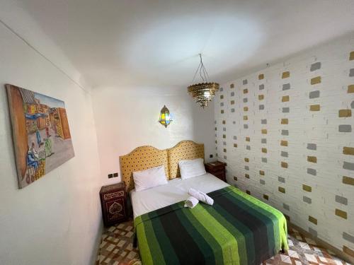 una camera con un letto con una coperta verde e bianca di Sun Hostel a Marrakech