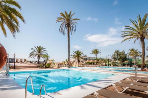 una piscina con palmeras y sillas en Hotel Portomagno by ALEGRIA, en Aguadulce