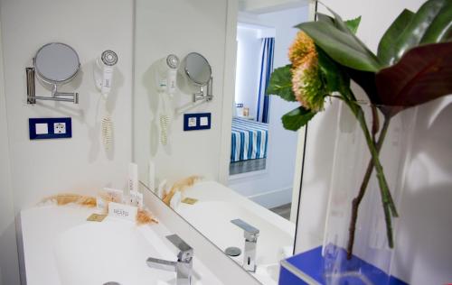 La salle de bains est pourvue d'un miroir et d'un vase avec une fleur. dans l'établissement ALEGRIA Sun Village, à Lloret de Mar