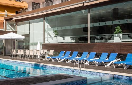 a pool with blue lounge chairs next to a building at ALEGRIA Mariner in Lloret de Mar