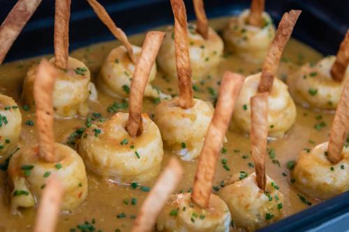 a group of shrimp on sticks in a dish of gravy at ALEGRIA Mariner in Lloret de Mar