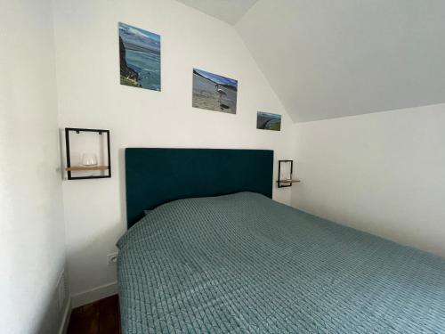 une chambre avec un lit et des tableaux au mur dans l'établissement La maison d'Amélie Cancale, à Cancale