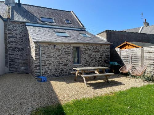 - une table de pique-nique et des chaises en face d'un bâtiment dans l'établissement La maison d'Amélie Cancale, à Cancale