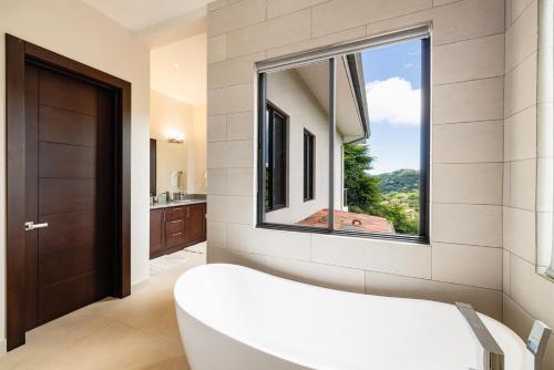 ein Bad mit einer großen Badewanne und einem Fenster in der Unterkunft Pacifico 13 - Casa Napoleon in Coco