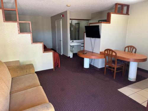 Rodeway Inn & Suites South of Fiesta Park في سان انطونيو: غرفة معيشة مع أريكة وطاولة مع تلفزيون