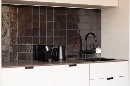 a kitchen with black tiles on the wall and a sink at By Friso Den Haag - Scheveningen in Scheveningen