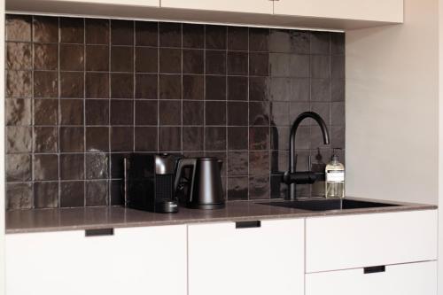 a kitchen with black tiles on the wall and a sink at By Friso Den Haag in Scheveningen