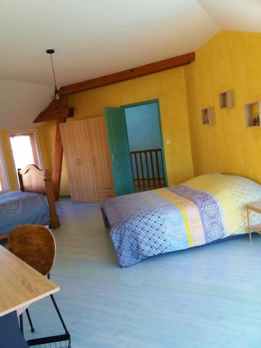 - une chambre avec 2 lits, une table et une porte dans l'établissement Gite Entre Pierre et Come, à Chablis