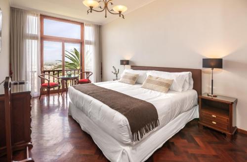 a bedroom with a large bed and a table and chairs at Hotel Altos de la Viña in San Salvador de Jujuy