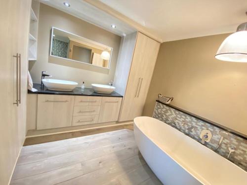 a bathroom with two sinks and a tub and a mirror at Loddey's Self Catering Apartments in Strand