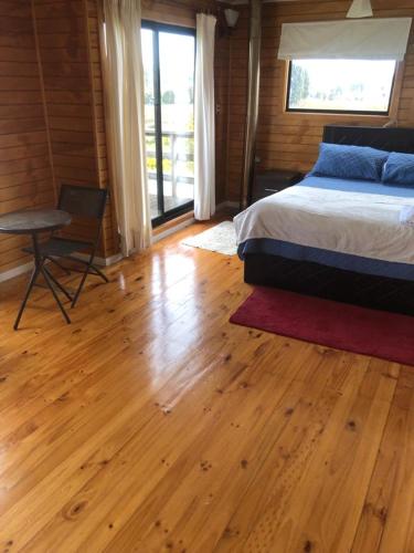a bedroom with a bed and a wooden floor at CASAS Y CABAÑAS CUMBRES DEL SOL in Castro