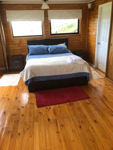 a bedroom with a bed with a red rug and two windows at CASAS Y CABAÑAS CUMBRES DEL SOL in Castro