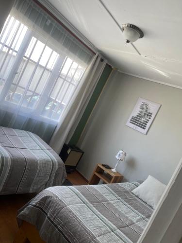 1 dormitorio con 2 camas y 2 ventanas en Hospedaje de la vita, en Punta Arenas