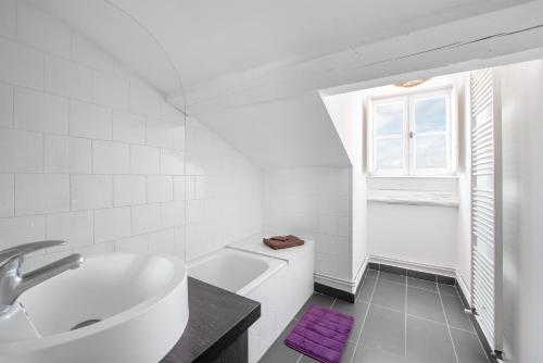 baño blanco con lavabo, bañera y ventana en T3 Duplex - Vue sur toits & Cité en Carcasona