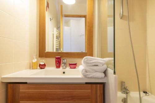 a bathroom with a sink and a mirror and a shower at Résidence & Spa Le Machu Pichu in Val Thorens