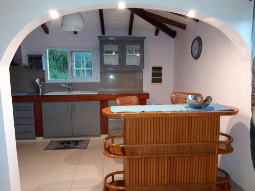 a kitchen with a table and a counter with chairs at Maison charmante avec piscine à Petit-Bourg. in Petit-Bourg