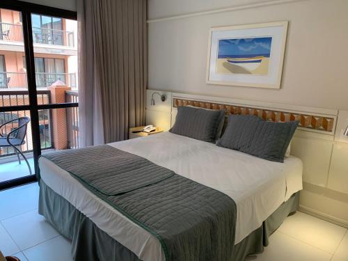 a bedroom with a large bed with a balcony at Studio no Jurerê Beach Village - Pé na areia in Florianópolis