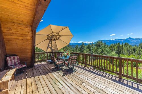 a deck with a table and chairs and an umbrella at Catamount Cabin in Ridgway