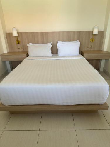 a large bed with white sheets and pillows on it at Srikrisna in Seminyak