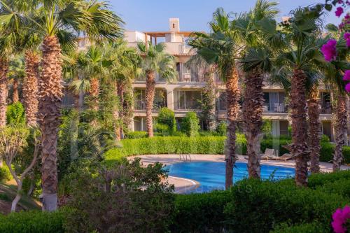 a building with palm trees and a swimming pool at Ladybird - Veranda Beach House in Hurghada